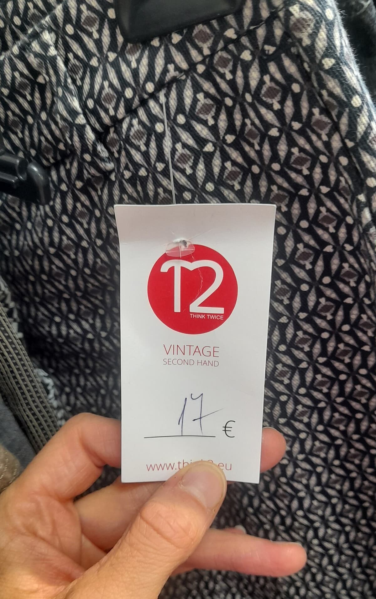 A hand holding a second-hand shop price tag marked 17 euros
